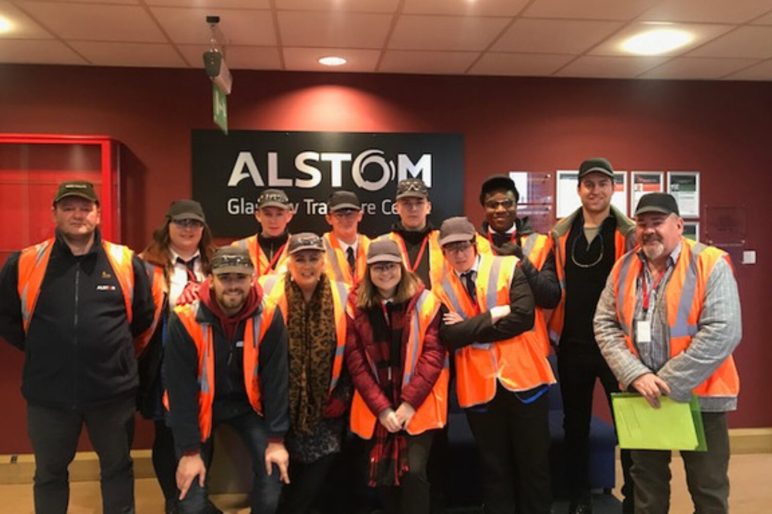 A group of people stood in a room in front of a sign alstom